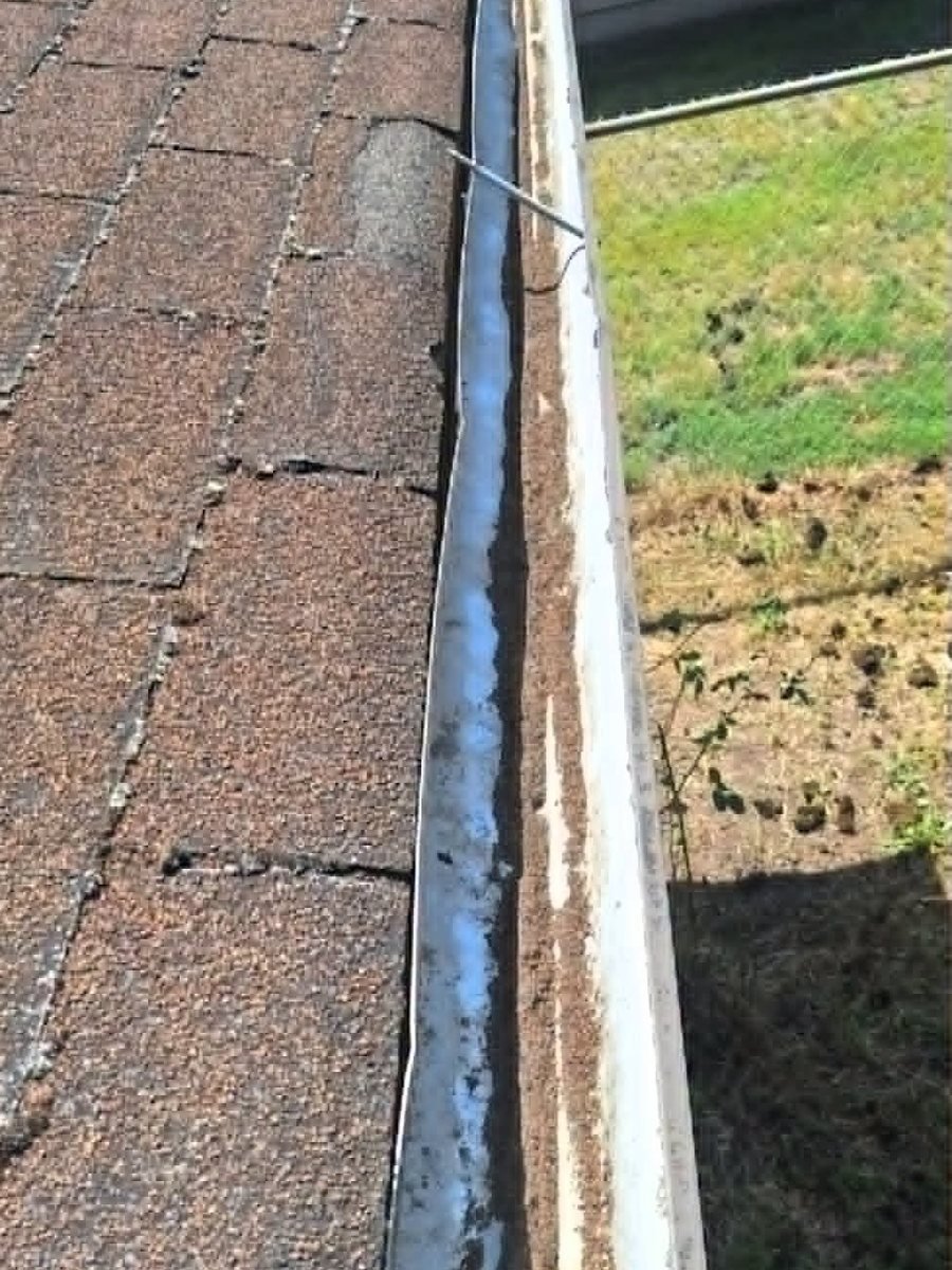 Shingle grit and standing water sitting in a gutter